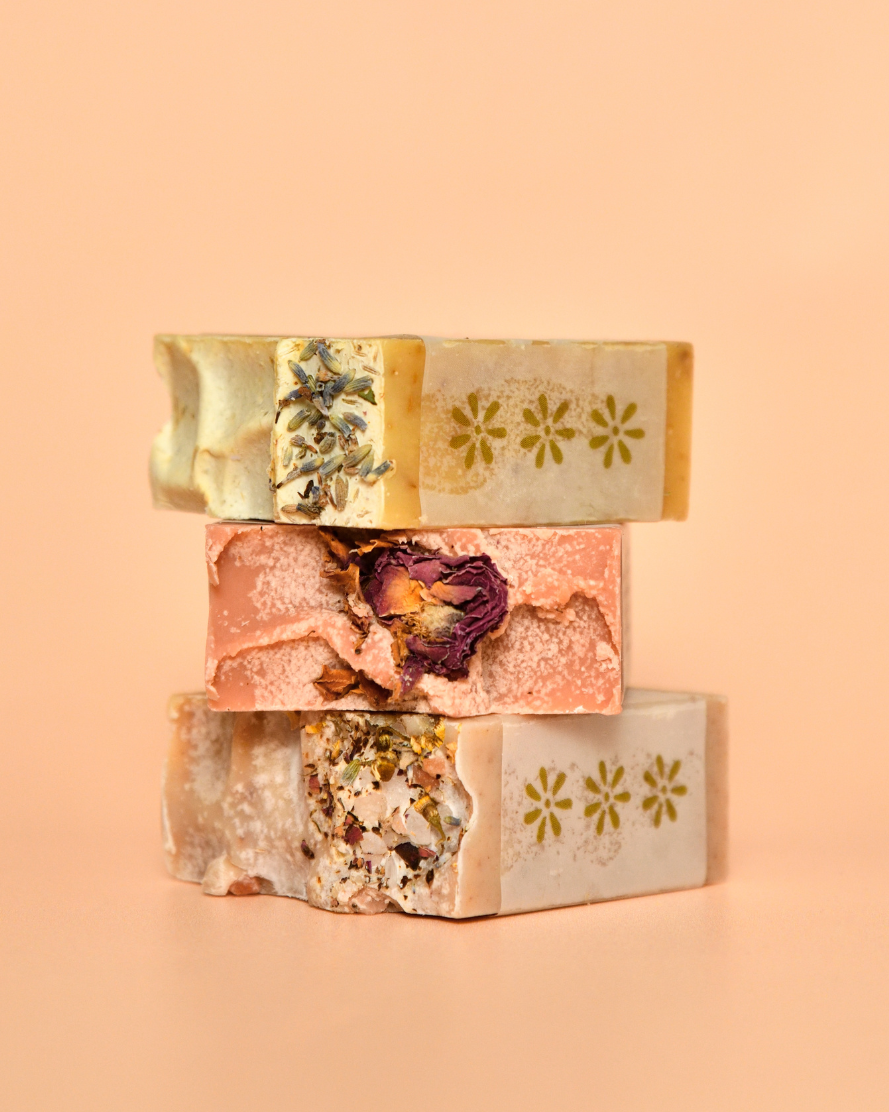 Three stacked soap bars with natural ingredients on a peach background