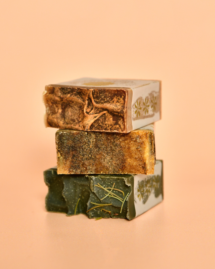 Three stacked soap bars with visible branding on a peach background