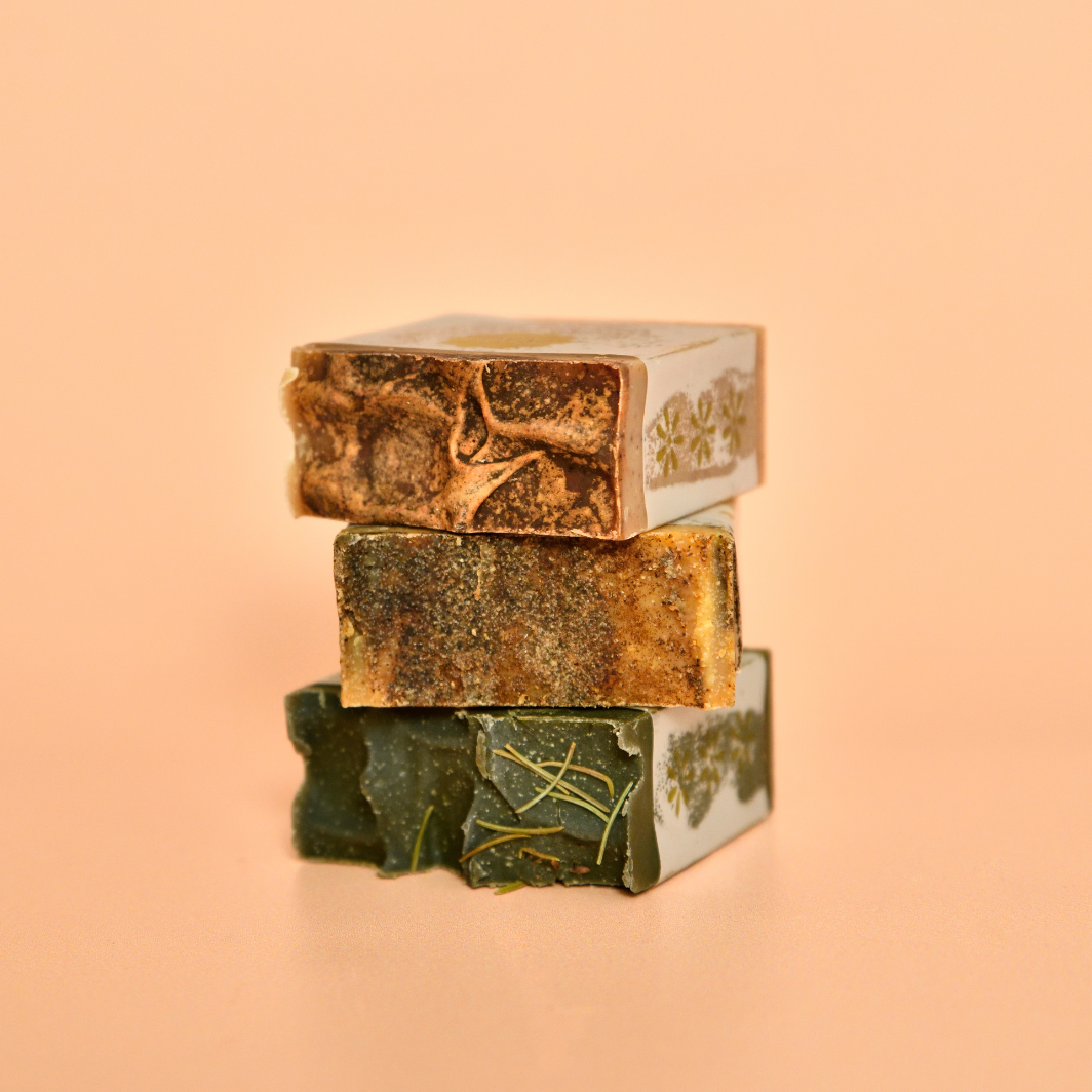 Three stacked soap bars with visible branding on a peach background